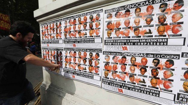 Man with poster showing 21 people tried for crimes at La Cacha in La Plata, Argentina 24 Oct 2014