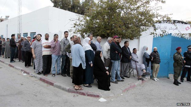 People wait in line outside a polling station to vote in Tunis October 26, 2014