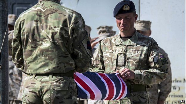 Two British soldiers hold a folded British flag