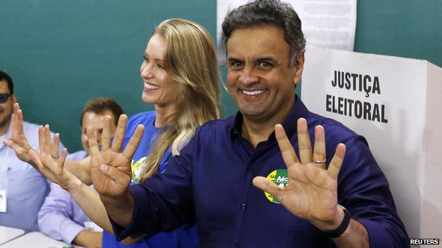 Presidential candidate Aecio Neves of the Brazilian Social Democracy Party (PSDB) and his wife Leticia Weber gesture to photographers as they arrive to vote in the runoff presidential election in Belo Horizonte, October 26, 2014