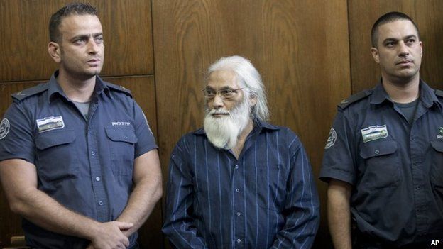 Goel Ratzon stands in between police officers in court