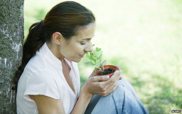 Woman smelling pot of herbs