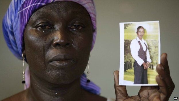 Martha Mark, the mother of kidnapped school girl Monica Mark cries as she displays her photo, in the family house, in Chibok, Nigeria (May 2014)