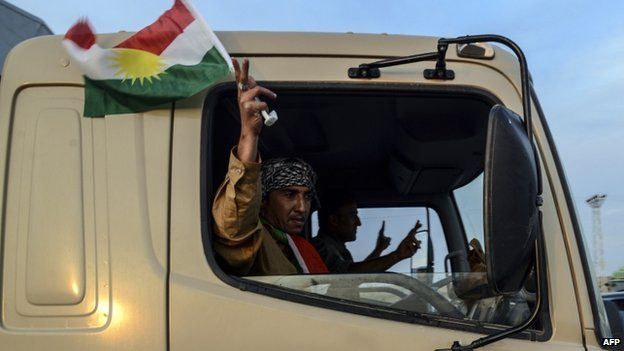 A peshmerga fighter waves a flag of Kurdistan as their convoys arrive in Viransehir, in Sanliurfa on 29 October 2014.