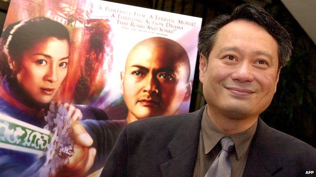 Director Ang Lee poses next to a poster for his film Crouching Tiger, Hidden Dragon