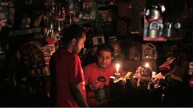 A Bangladeshi salesman interacts with a customer during a blackout in Dhaka - 1 November 2014