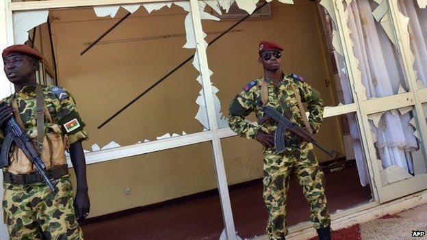 Troops stand guard outside the national television headquarters in Ouagadougou on November 2