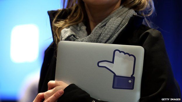 Woman holds laptop with thumbs-up 'like' logo