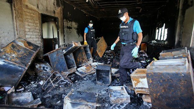 Thai forensic police inspect the burnt remains of the district government bureau after it was allegedly set alight by Muslim militants in Pattani province on October 28, 2014.
