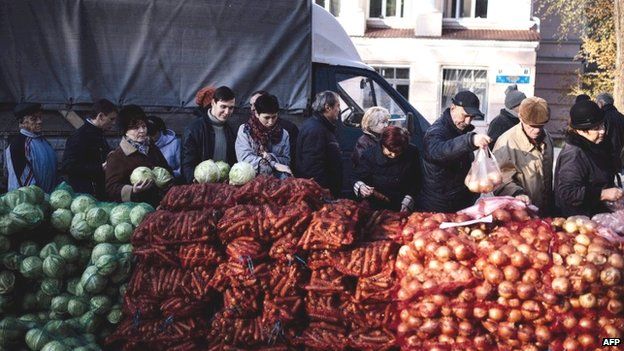 People stand in line to buy cheap vegetables in front of a polling station in Donetsk