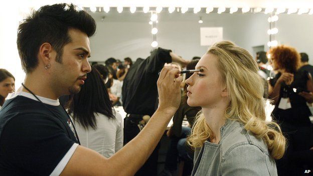 A make-up artist applying eye shadow to a model