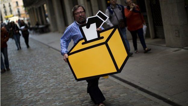 Businessman Emilio Busquets carries a drawing of a ballot box to decorate his shop ahead of voting on an informal poll, scheduled for next Sunday, in Girona, Spain, on Saturday Nov.8, 2014