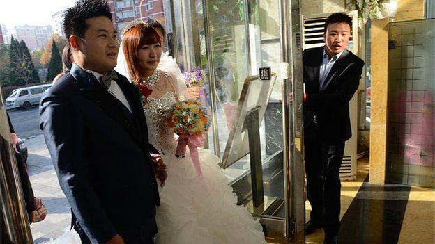 A newly-married couple (C) walk into a restaurant near the China National Convention Center (CNCC), where the annual Asia-Pacific Economic Cooperation (APEC) Summit is being held in Beijing on November 8, 2014