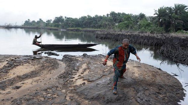 A man walks on slippery spilled crude oil on the shores and in the waters of the Niger Delta swamps of Bodo, a village in the famous Nigerian oil-producing Ogoniland, which hosts the Shell Petroleum Development Company (SPDC) in Nigeria's Rivers State on June 24, 2010.