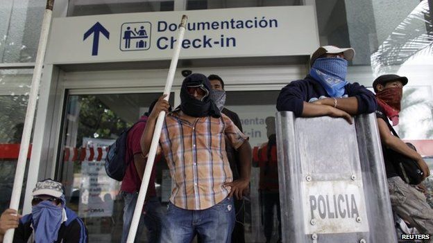 Masked protesters stand outside Acapulco airport on 10 November, 2014