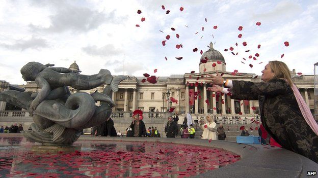 A lady throws poppies in to the fountain in Trafalgar Square on Armistice Day 11 November 2014