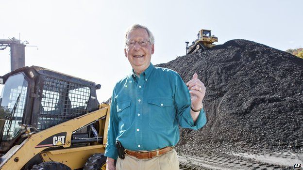 US Senator Mitch McConnell stands in front of a large mound of coal.
