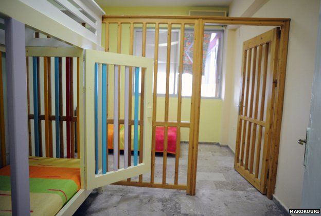 A caged bed and wooden bars separating a section of a room - some of the wood has been painted