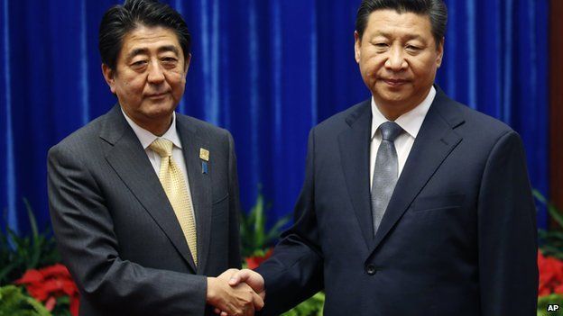 In this file photo taken on 10 November, 2014, Japanese Prime Minister Shinzo Abe and China's Xi Jinping shake hands during their meeting at the Great Hall of the People in Beijing