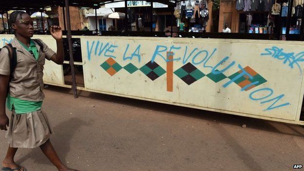 A schoolgirl walks past graffiti "Blaise go away" "Long live the revolution" on November 6, 2014 in Ouagadougou