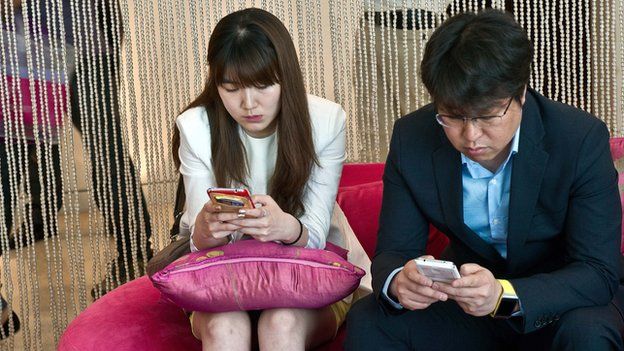 A man and a woman using their smartphones