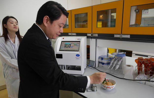 Video still of scientists testing a bowl of tom yum gung