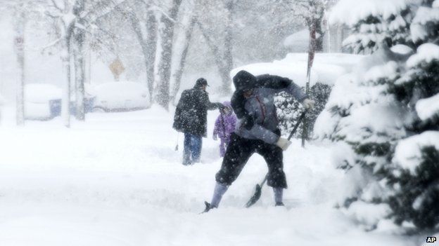 Residents shovel their sidewalks along Coit Avenue in the wind and snow in Grand Rapids, Mich.