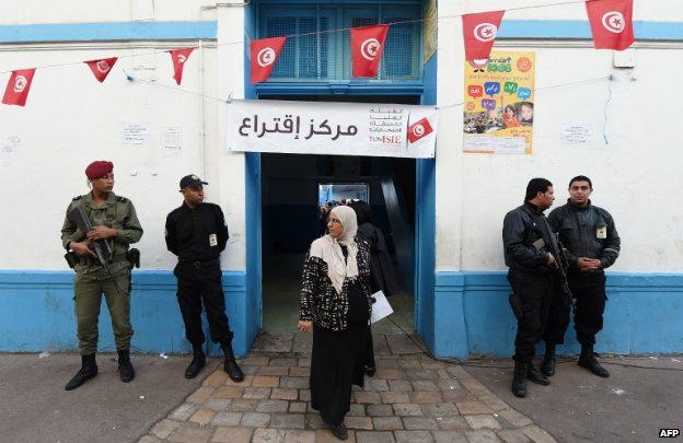 Tunisian security officers stand guard outside at a polling station in Tunis - 23 November 2014
