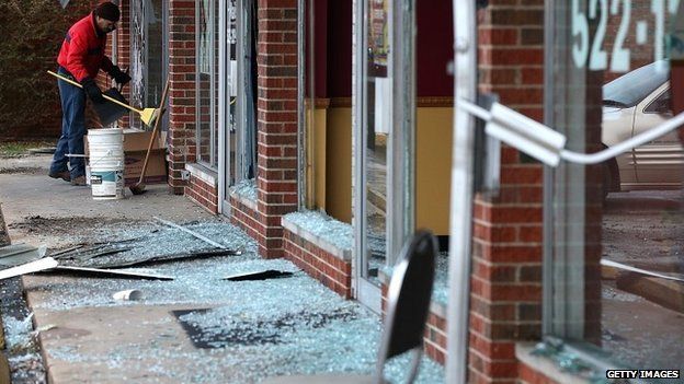 A worker cleans up glass at a building damaged during riots in Dellwood, Missouri - 25 November 2014