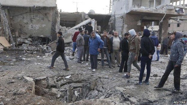 People inspect a site in Raqqa after it is hit in what activists said was a Syrian government air strike on 25 November 2014