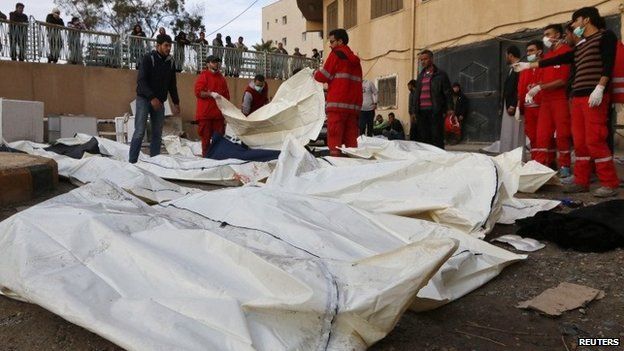 Emergency services personnel gather the bodies of the victims of what activists said were government air strikes in Raqqa, Syria (25 November 2014)