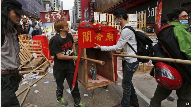 Protesters remove the Chinese Taoist God of War, Guan Yu, set up at a barricade at an occupied area as police keep clearing away them in Mong Kok district of Hong Kong Wednesday, 26 November 2014.