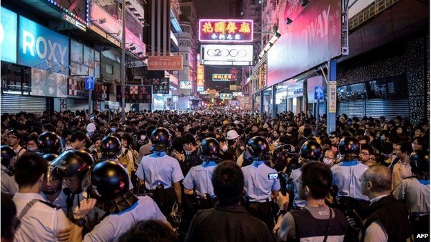 Police officers stand guard as pro-democracy protesters gather on a road in the Mong Kok district of Hong Kong in the early hours of 27 November 2014