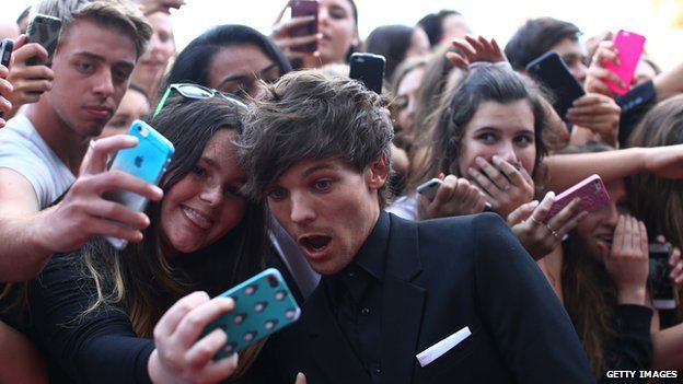 One Direction's Louis Tomlinson takes pictures with fans