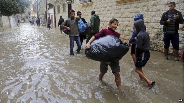 Palestinians carry their belongings as they leave their flooded family house during heavy rain in Gaza City, northern Gaza Strip, 27 November 2014