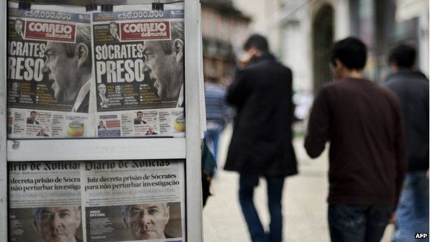 People pass by a kiosk displaying Portuguese newspapers' front cover with a picture of former Portuguese Prime Minister Jose Socrates in Lisbon on 25 November 2014