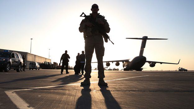 A soldier stands guard near a C17 military aircraft sitting on the tarmac, on 8 December 2013 in Kandahar.