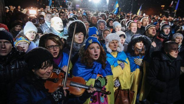 Ukrainians sing the national anthem as they attend a rally marking the first year anniversary of the protests