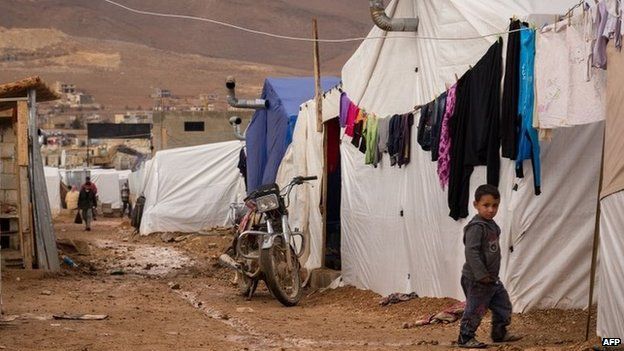 A young Syrian refugee walks past tents at the al-Nihaya camp in eastern Lebanon (25 November 2014)