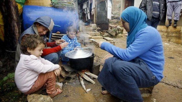 Syrian refugees prepare food near their tent at a camp in Lebanon's Chouf mountains (11 December 2013)