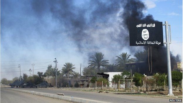 Smoke rises behind an Islamic State flag in Diyala province, Iraq, 24 November 2014