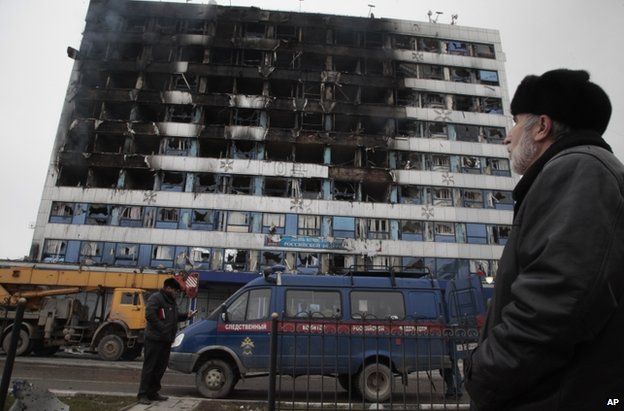 A man looks up at the burnt publishing house in Grozny, 4 December