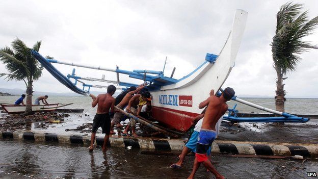 Filipino fishermen carry a fishing boat as strong winds brought by an upcoming typhoon hits Legazpi city, Albay province, Philippines, 5 December 2014