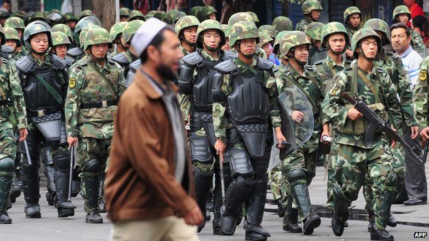Armed Chinese soldiers march on patrol as a Uighur man crosses the street in Urumqi on 15 July, 2009 in northwest China's Xinjiang province