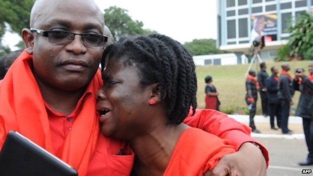 A man comforts a woman crying after viewing the body of late President John Atta Mills at the parliament in Accra on 8 August 2012