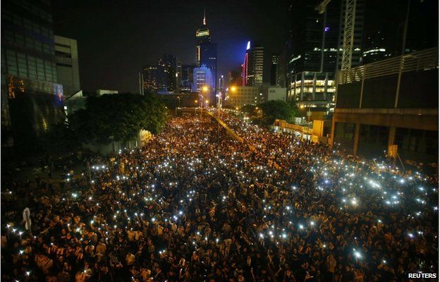 Protesters hold their mobile phones as they block the main street to the financial Central district, outside the government headquarters, in Hong Kong 29 September 2014