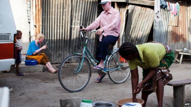 Fikiri Sultan (C), a member of Tanzania's Albino United football club, rides his bicycle in front of his home in Dar es Salaam on 3 November 2010