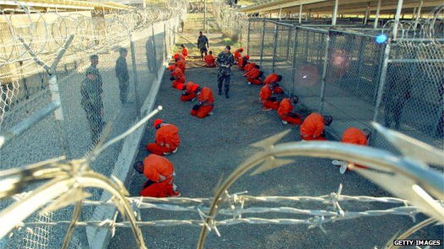 U.S. Military Police guard Taliban and al Qaeda detainees in orange jumpsuits January 11, 2002