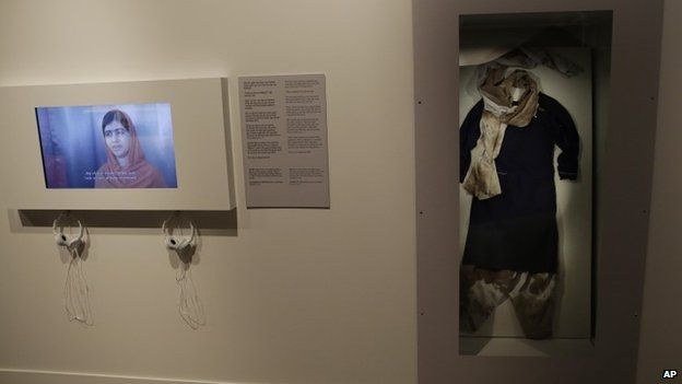 The blood-stained school uniform joint Nobel Peace prize winner Malala Yousafzai was wearing when she was shot by the Taliban is displayed next to an image of Malala speaking on a screen at the Nobel Peace Center in Oslo, Norway (9 December 2014)