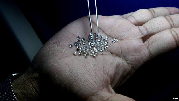 In this photograph taken on December 5, 2014, an Indian supervisor looks at the finished diamonds on a production line at a processing centre in Surat, some 265km south of Ahmedabad.